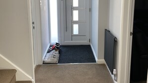 A hallway with a carpeted floor, a radiator, and a door with a window.