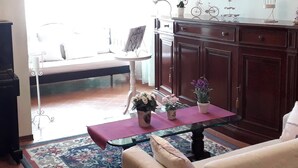 Un salon comprenant un canapé, une table basse avec un vase, un meuble et un mur orné de tableaux encadrés.