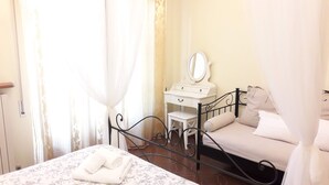Une chambre à coucher comprenant un lit, une table de chevet, une commode, un miroir et une fenêtre avec des rideaux.