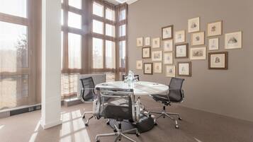 A conference room with a round table, four chairs, and framed pictures on the wall.