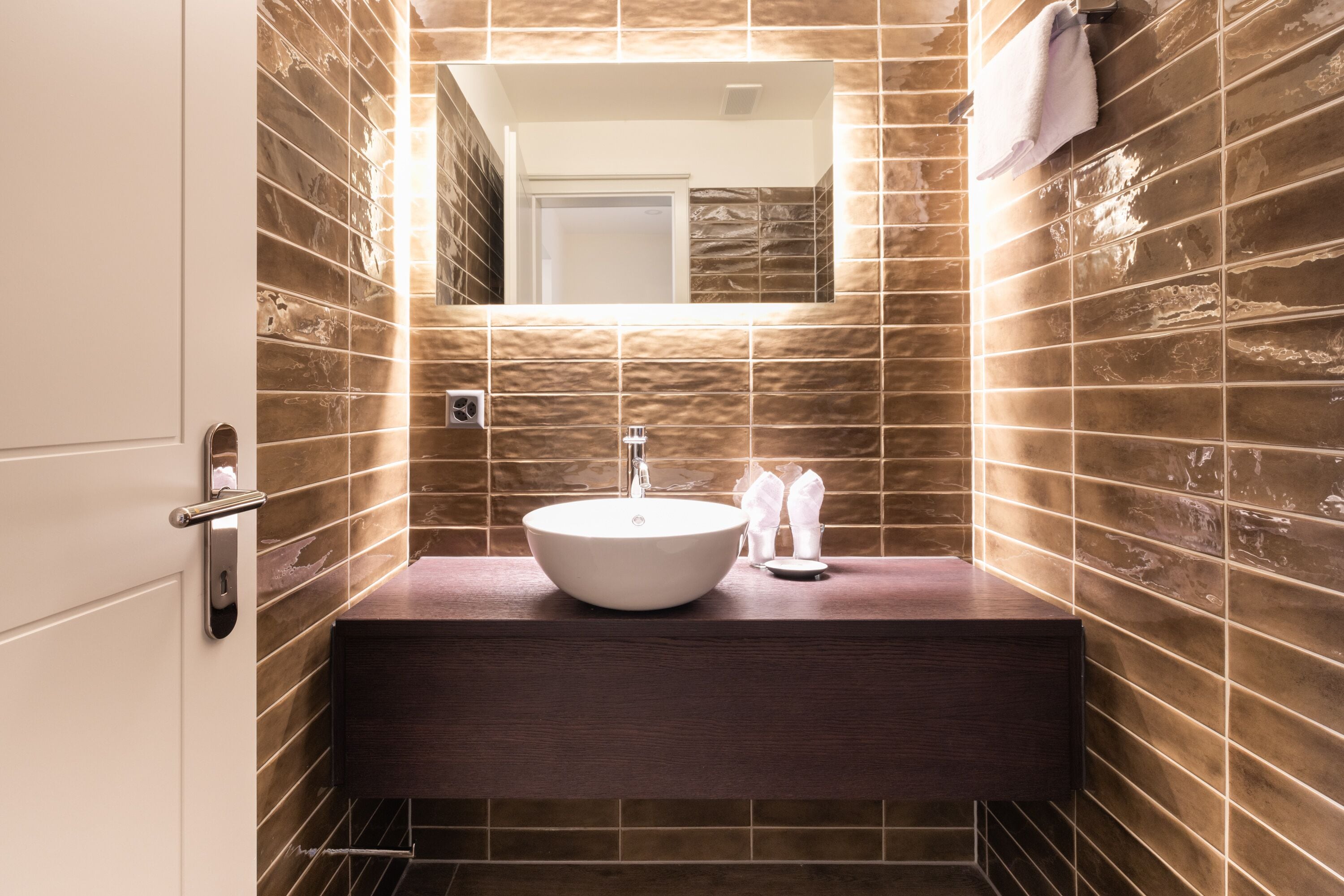 A bathroom with a large mirror, a sink, and a towel hanging on the wall.