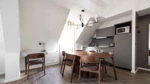 Una cocina moderna con comedor, que incluye una mesa y sillas de madera, un microondas integrado y una lámpara colgante.