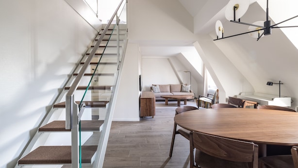 Un interior moderno con una escalera, un comedor y una sala de estar.