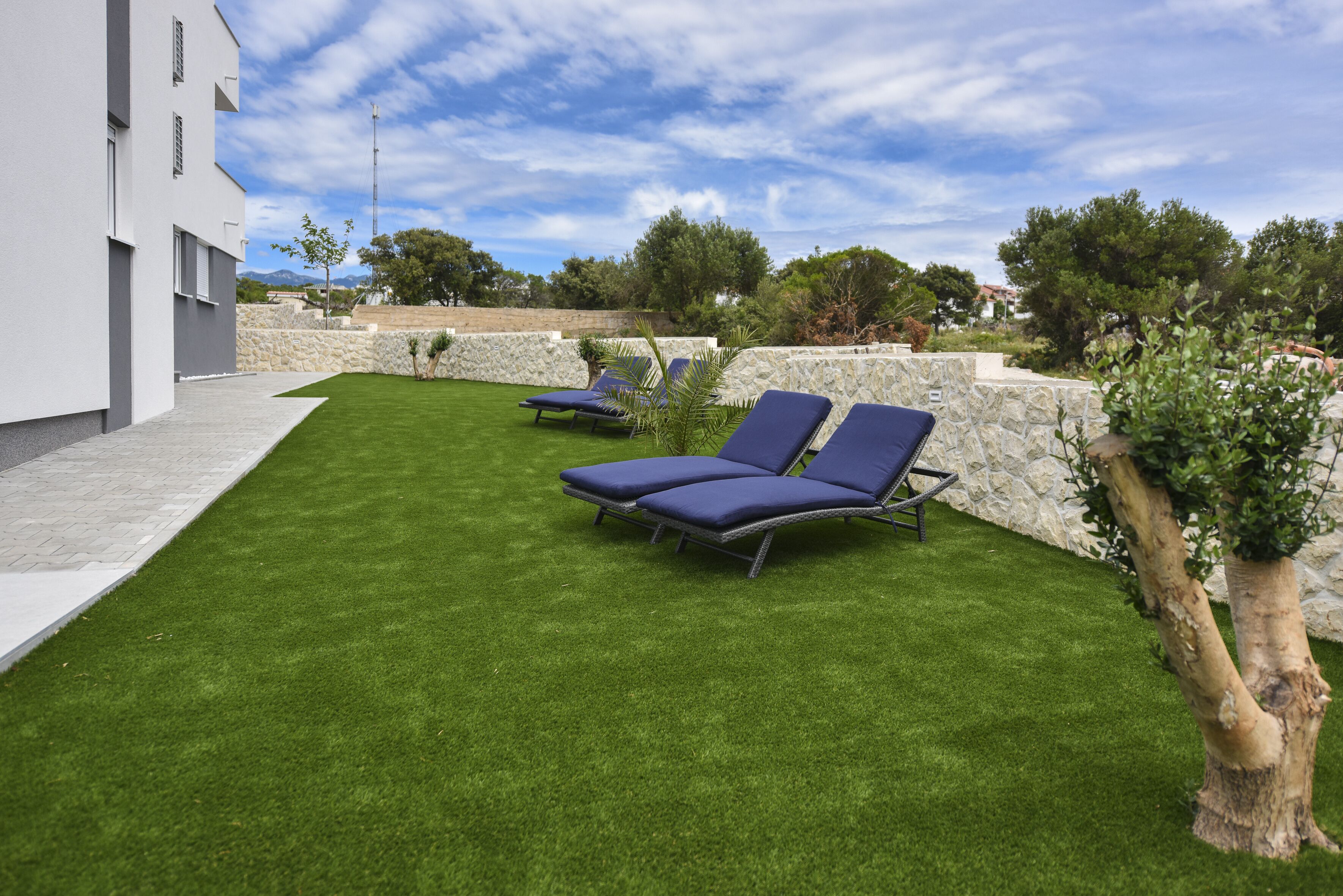 Un espace extérieur moderne comprenant deux fauteuils de jardin et une pelouse bien entretenue.