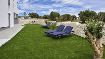 Un espace extérieur moderne comprenant deux fauteuils de jardin et une pelouse bien entretenue.