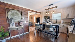 A modern kitchen with wooden cabinets, a central island, and pendant lighting. - Creekside Cottages : Sneffles Mountain Luxury in Town (Blairsville)