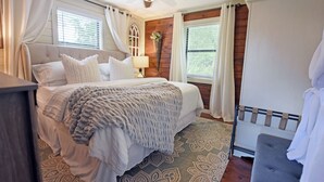 A bedroom with a large bed, a ceiling fan, and a window with curtains. - Creekside Cottages : Sneffles Mountain Luxury in Town (Blairsville)