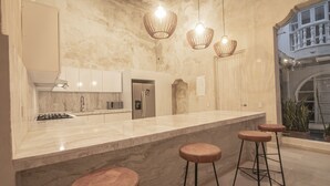 A modern kitchen with a marble countertop, stainless steel appliances, and a large island with bar stools. - 7 Bedroom Beautiful Mansion in the Old City (Cartagena)