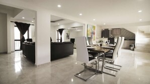 Un interior moderno con zona de comedor, sofá y escalera.