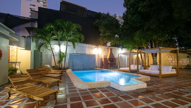 A pool area with lounge chairs and a wooden cabana.