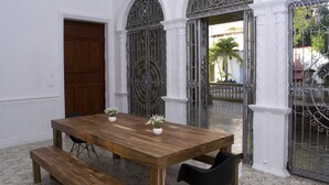 A wooden dining table with benches, white walls, and decorative iron gates.