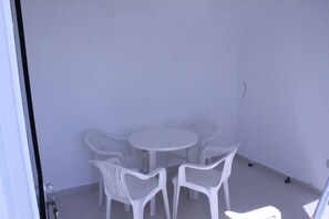Een kamer met een witte tafel en vier witte stoelen.