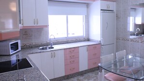 A kitchen with white cabinets, a microwave, a sink, and a glass table. - Mele Sky Beach, 1, sea views, terrace and sun (Lomo Quiebre)