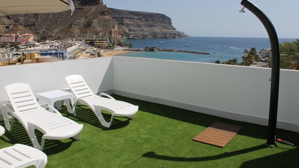 A balcony with artificial grass, white lounge chairs, and a view of the sea and cliffs. - Mele Sky Beach, 1, sea views, terrace and sun (Lomo Quiebre)