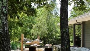 A hammock in a garden with trees and a building in the background. - Gorgeous Mountain View,  6 Private acres, Close to Downtown! (Hot Springs)