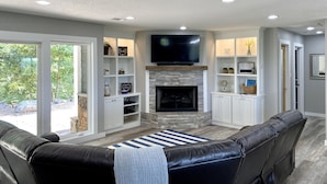 A living room with a fireplace, a flat-screen TV, and a leather sofa. - Gorgeous Mountain View,  6 Private acres, Close to Downtown! (Hot Springs)