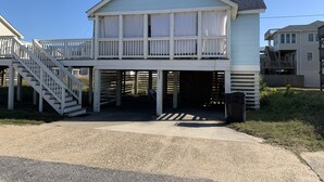 A two-story house with a balcony, a covered entryway, and a staircase leading to the upper level. - The Pirates' 2 Bedroom Cottage by RedAwning (Kitty Hawk)