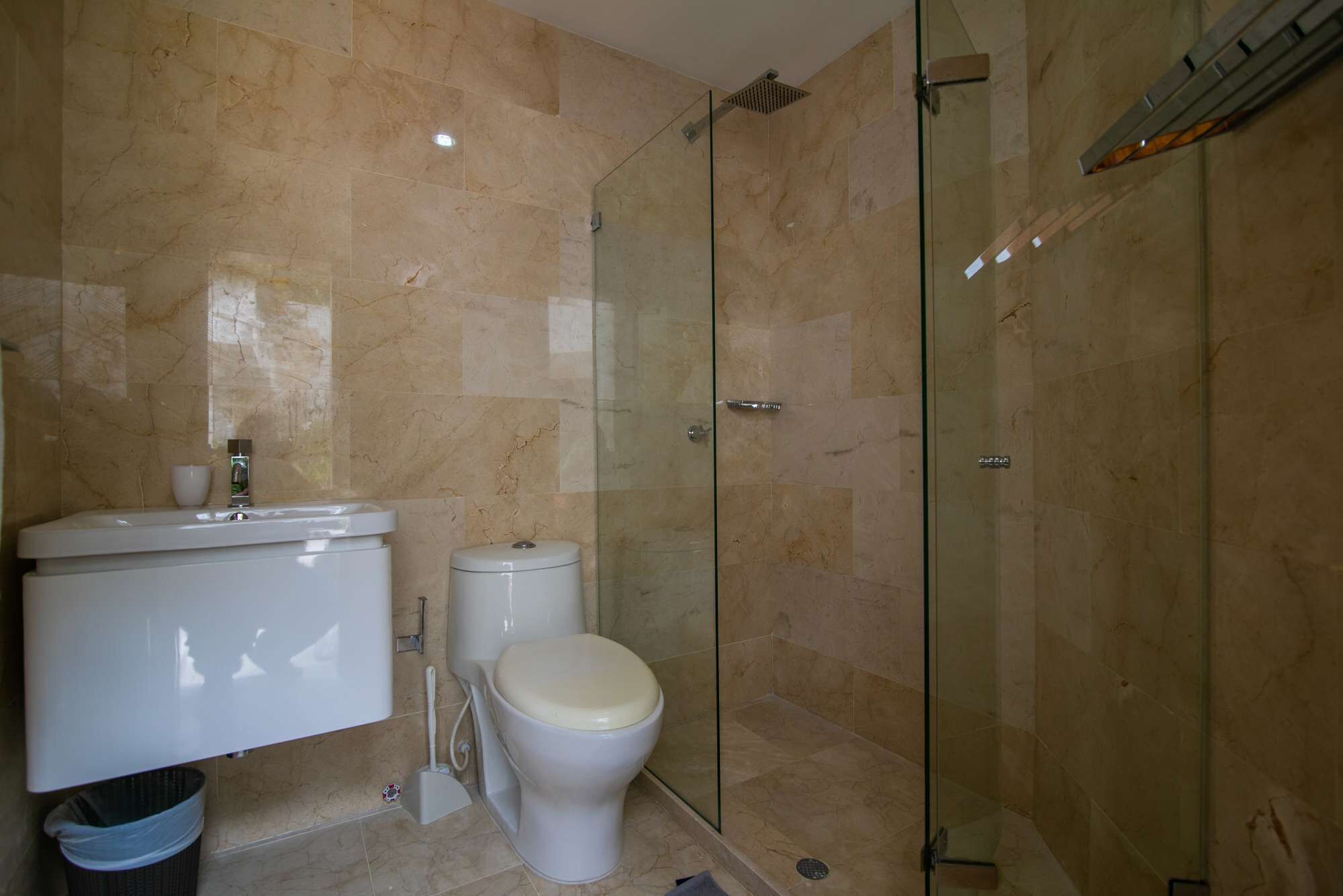 Une salle de bain équipée de toilettes, d’un bidet et d’une douche à parois de verre.