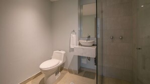 Une salle de bain moderne équipée de toilettes, d’un lavabo et d’une douche à parois de verre.