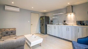 A modern kitchen with a built-in stove, a refrigerator, and a microwave. There is a white countertop with a sink and a range hood above the stove. - Brand New 1 BR Apartment in Bocagrande (Cartagena)