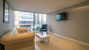 A modern living room with a sofa, a coffee table, and a TV mounted on the wall.