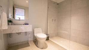 A modern bathroom with a white sink, toilet, and shower.