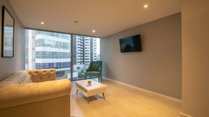 A modern living room with a sofa, a small coffee table, a green armchair, and a TV mounted on the wall. - 1 Bedroom Stunning Apartment in Bocagrande (Cartagena)
