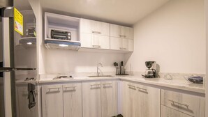 A compact kitchen with white cabinetry, a built-in toaster, a coffee maker, and a sink. - 1 Bedroom Stunning Apartment in Bocagrande (Cartagena)