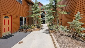 A building with a wooden exterior, a central pathway, and small trees.