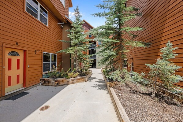Un bâtiment à l’extérieur en bois, avec un chemin central et de petits arbres.
