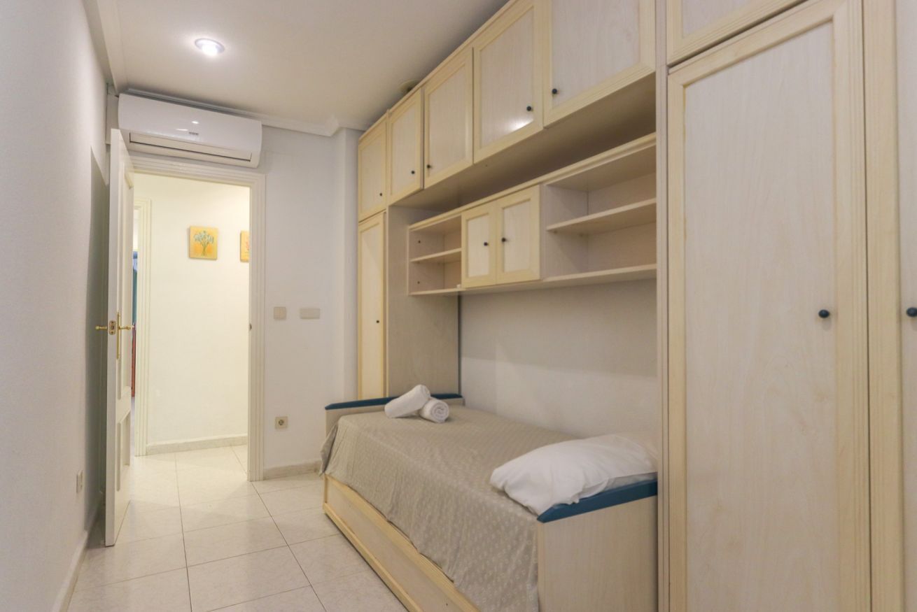 Quarto com cama, guarda-roupa de madeira e porta para outro cômodo.