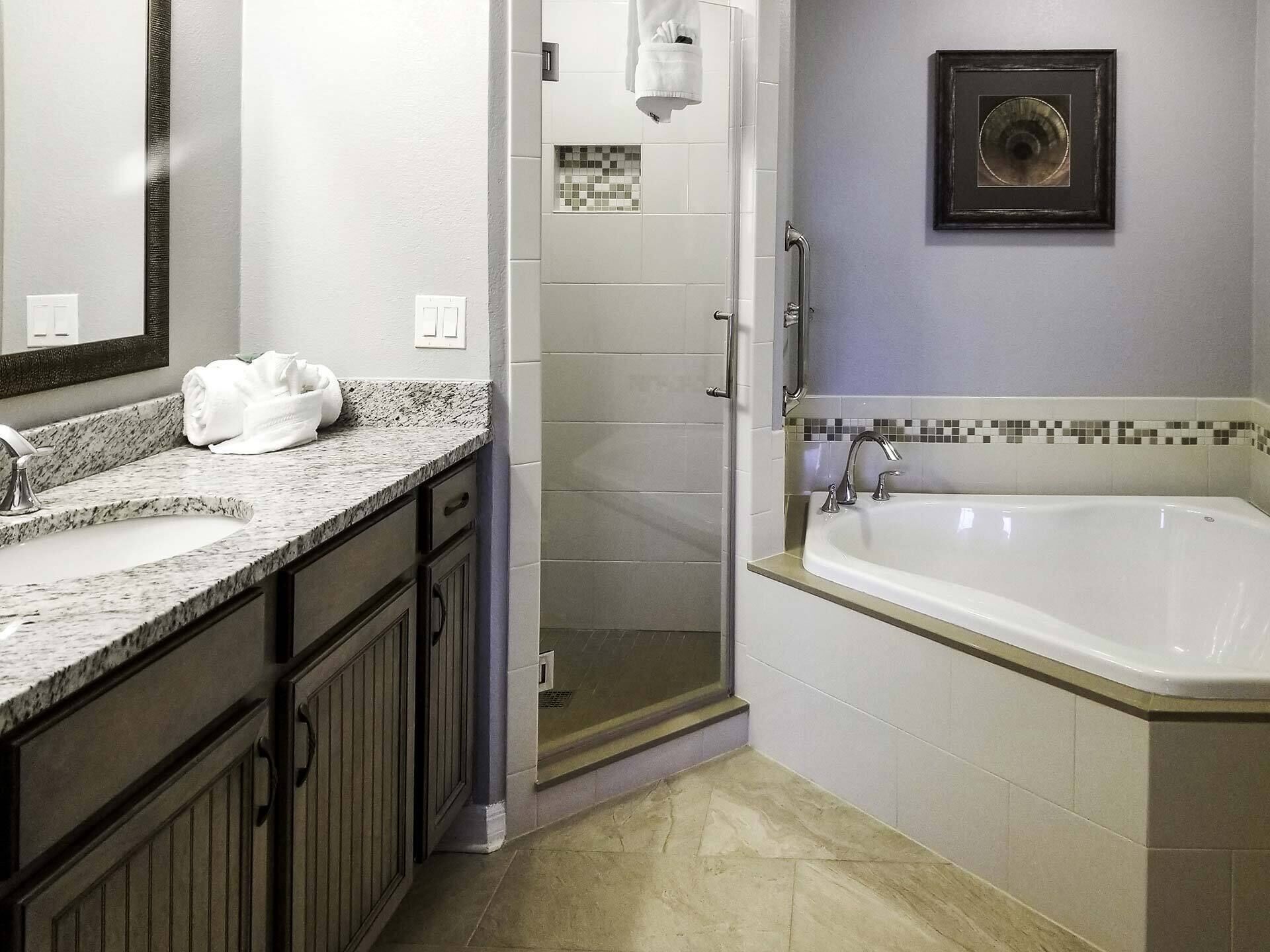 Une salle de bain avec un lavabo en marbre, une baignoire, une douche et un tableau encadré au mur.