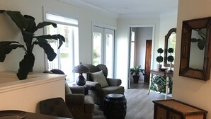 Un salon spacieux agrémenté d’une grande plante, d’un canapé, d’une table basse et d’une table à manger.