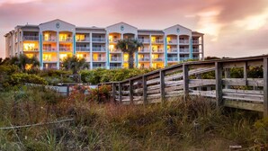 A multi-story hotel with balconies and a wooden walkway leading to the entrance.