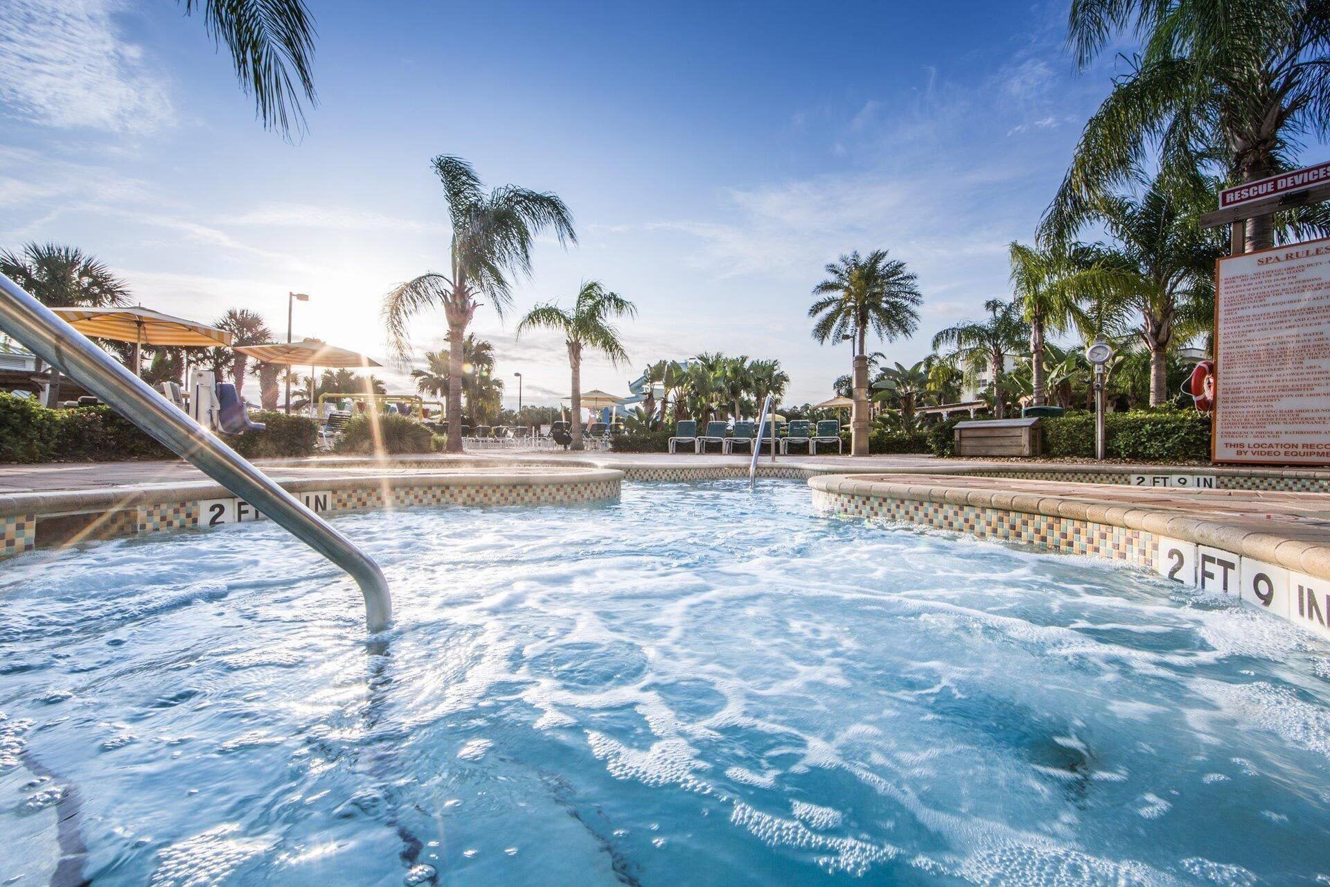 A pool area with a hot tub, palm trees, and a lifeguard stand.