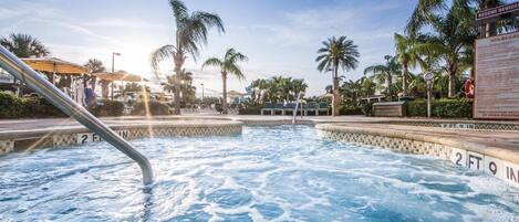 A pool area with a hot tub, palm trees, and a lifeguard stand.