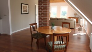 A dining area with a round wooden table, four chairs, and a potted plant.