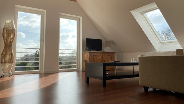 A spacious loft with high ceilings, skylights, and large windows offering views of the outdoors.