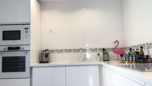 Une cuisine moderne avec des meubles blancs, un four à micro-ondes, un four traditionnel, un évier et un flamant rose décoratif.