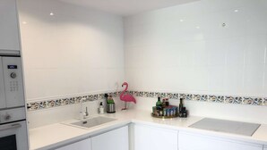 Une cuisine moderne avec des armoires blanches, un évier double et un crédence décorative en carreaux.