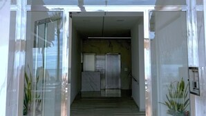 L’entrée d’un hôtel, avec une façade en marbre, une porte en verre et un couloir menant à l’accueil.