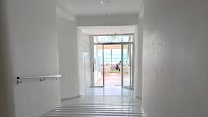Un couloir carrelé mène à une porte vitrée donnant sur la plage.