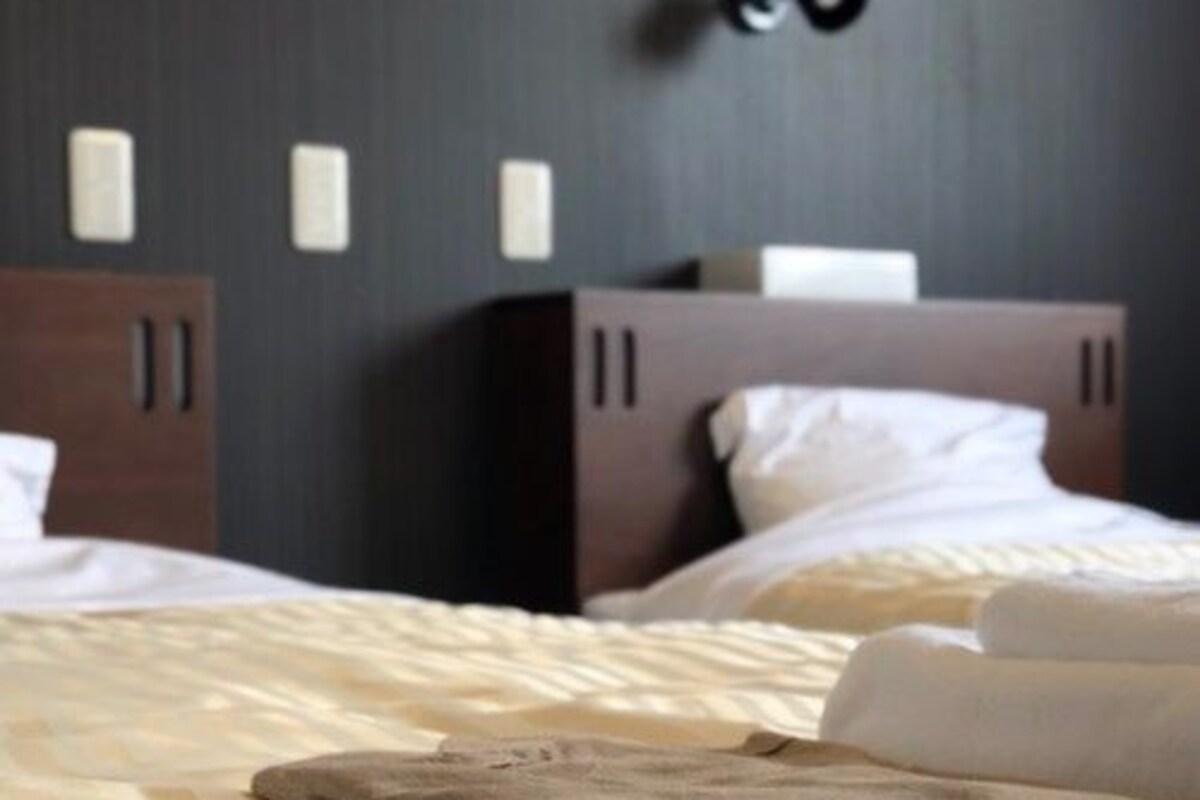 Una habitación de hotel con cama, mesita de noche y armario.