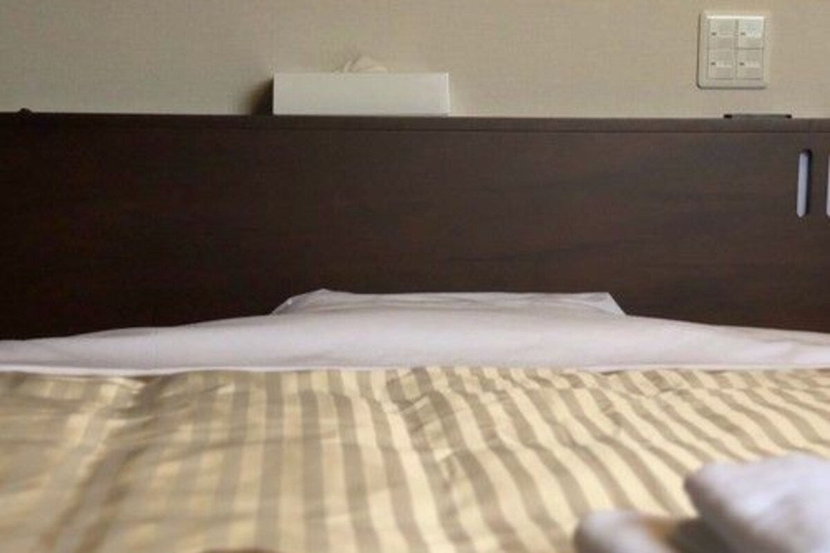 Una cama con una colcha a rayas, una toalla doblada y un objeto marrón sobre la cama.