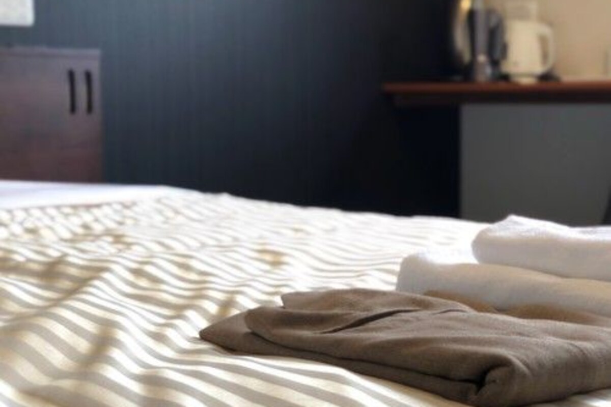 Una cama bien hecha con ropa de cama a rayas y ropa doblada encima.