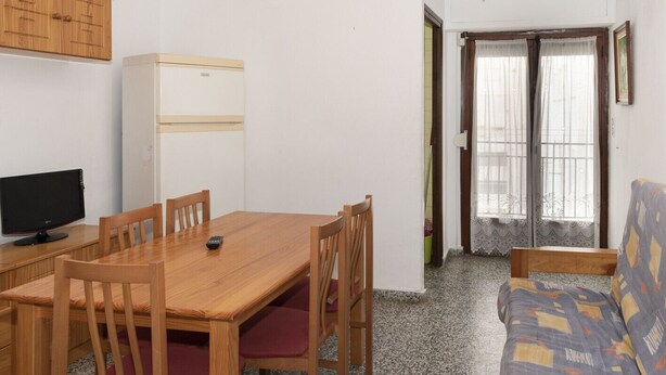 A compact living space with a wooden dining table, chairs, a sofa, a TV, and a refrigerator. - PROVENCE, 5º-17 (Cullera)