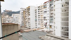 A view of a residential area with multi-story buildings, balconies, and a distant hill with a structure. - PROVENCE, 5º-17 (Cullera)