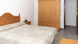 A bedroom with a wooden bed, a nightstand with a lamp, and a wardrobe. - PROVENCE, 5º-17 (Cullera)