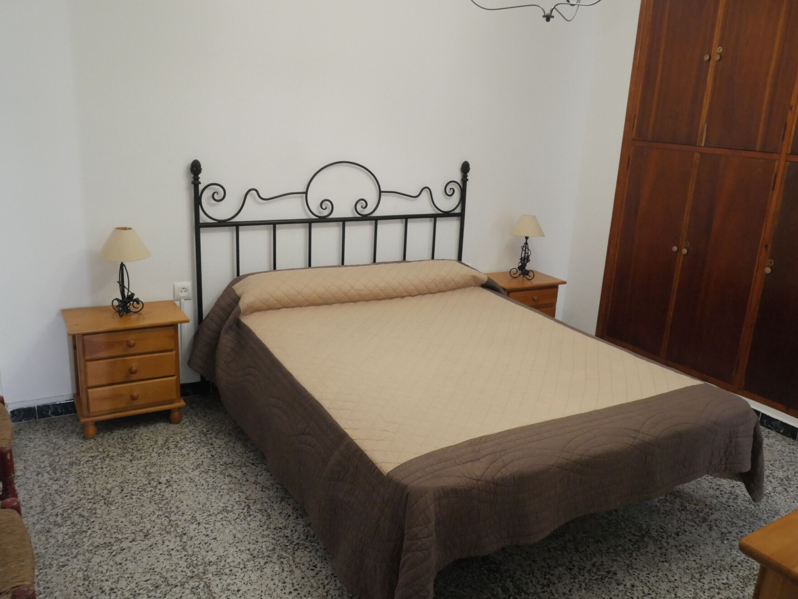 Ein Schlafzimmer mit einem Bett, zwei Nachttischen, einem Kleiderschrank und einem Teppichboden.