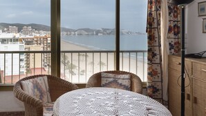 Un balcon agrémenté de meubles en osier, une vue sur la plage et un paysage urbain en arrière-plan.